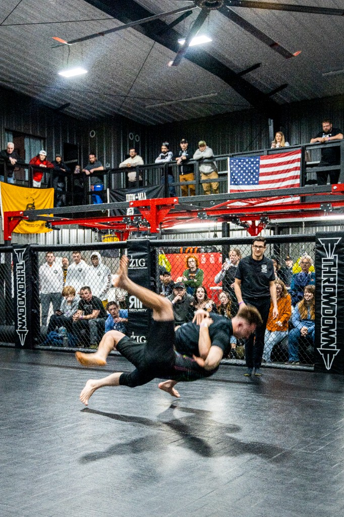 Athletes in cage during slam or takedown peak moment vertical frame
