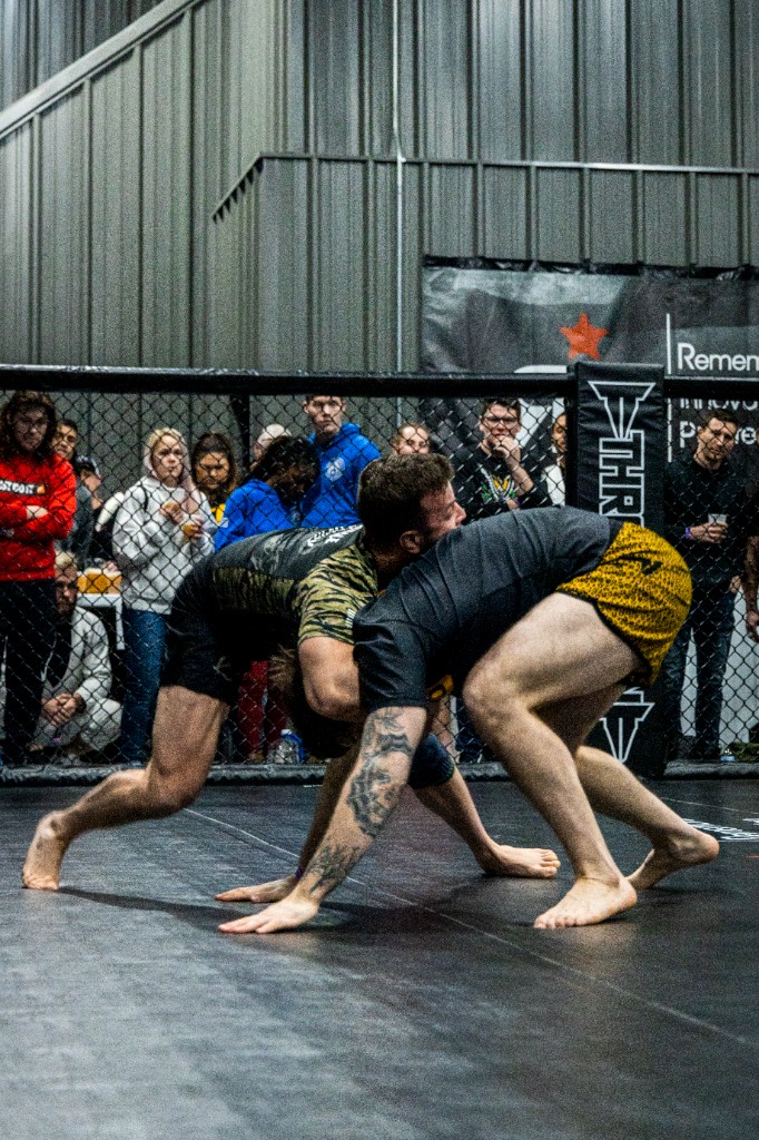 Two athletes in clinch against cage vertical composition