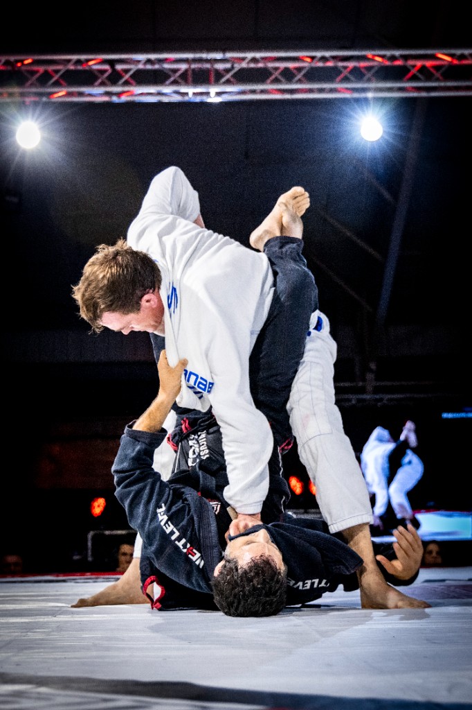 Gi guard exchange with athletes in colored kimonos vertical frame