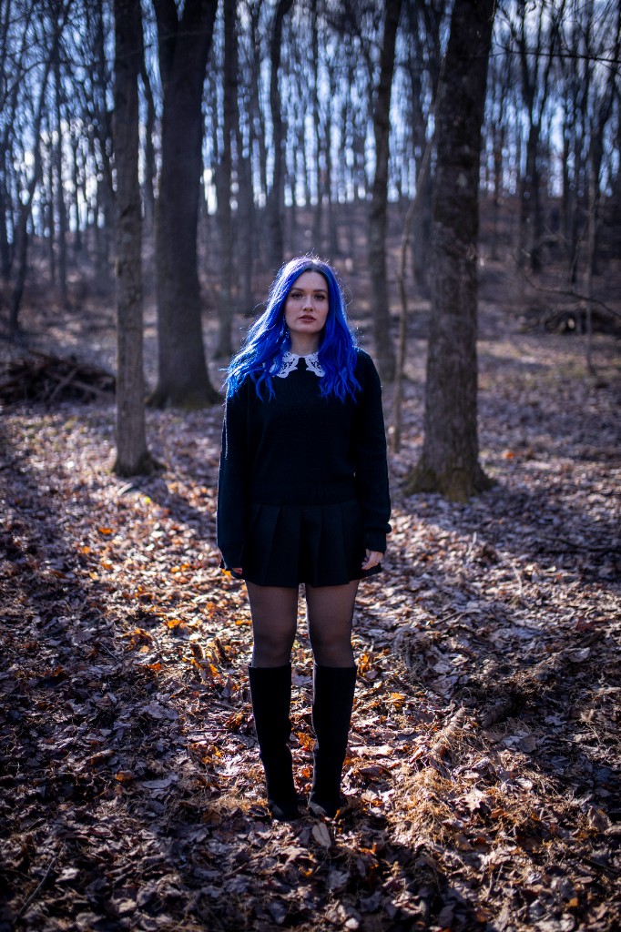 Wide shot of artist in lavender coat in forest environment