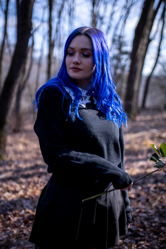 Surreal forest scene with artist bound to tree holding bouquet