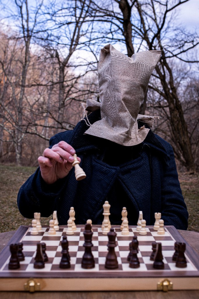 Conceptual portrait with giant chess pieces and artist in dramatic pose